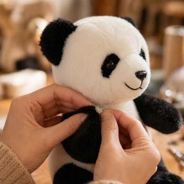 Mains inspectant les coutures d'une peluche panda