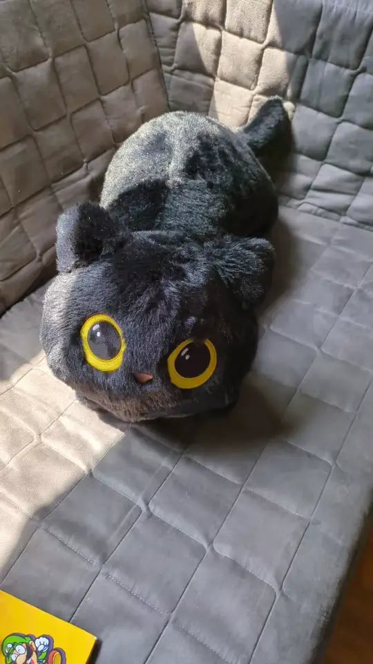 Peluche chat noir douce avec grands yeux, idéale comme coussin ou décoration.