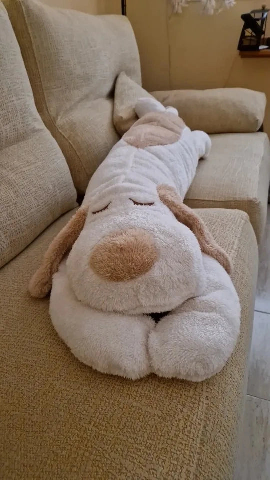 peluche chien géant allongé sur un canapé format boudin blanc et beige yeux fermés